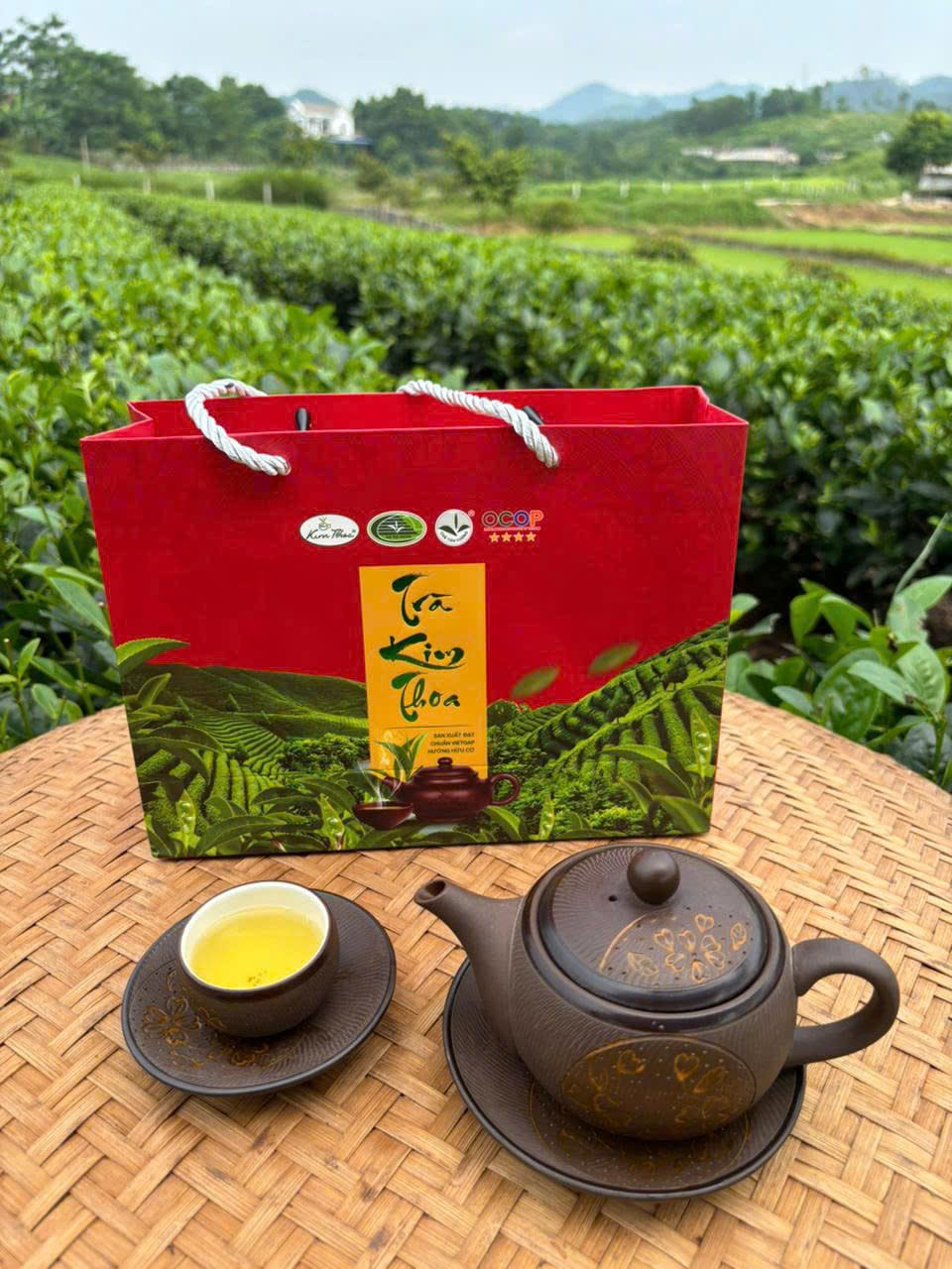 Hộp quà Trà Kim Thoa đứng cùng ấm chén trên mẹt tre